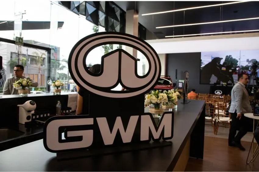 Great Wall Motor Company logo sitting on a table inside a Mexico City GWM dealership with workers and clients inside