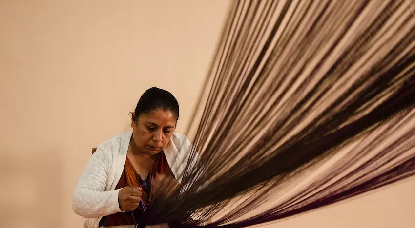 A Mexican artisan weaving with a traditional 'telar de cintura' in Santa María del Río.