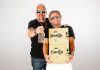 Celebrity chef Guy Fieri, left, and rocker Sammy Hagar, right, holding boxes and a bottle of their brand of tequila, Santo as they pose for a publicity photo