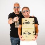 Celebrity chef Guy Fieri, left, and rocker Sammy Hagar, right, holding boxes and a bottle of their brand of tequila, Santo as they pose for a publicity photo