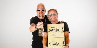 Celebrity chef Guy Fieri, left, and rocker Sammy Hagar, right, holding boxes and a bottle of their brand of tequila, Santo as they pose for a publicity photo