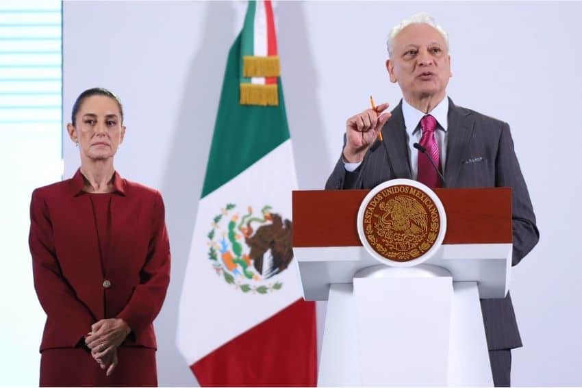 Mexico's President Claudia Sheinbaum standing stage left as Pemex director Victor Rodriguez Padilla stands at the presidential podium with a pencil in his hand and in mid-speech to reporters