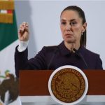 President Claudia Sheinbaum holds up her closed right hand while making a point while standing at the presidential podium during her Nov. 21 press conference at Mexico's National Palace.