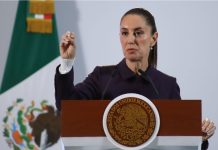 President Claudia Sheinbaum holds up her closed right hand while making a point while standing at the presidential podium during her Nov. 21 press conference at Mexico's National Palace.