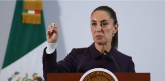 President Claudia Sheinbaum holds up her closed right hand while making a point while standing at the presidential podium during her Nov. 21 press conference at Mexico's National Palace.