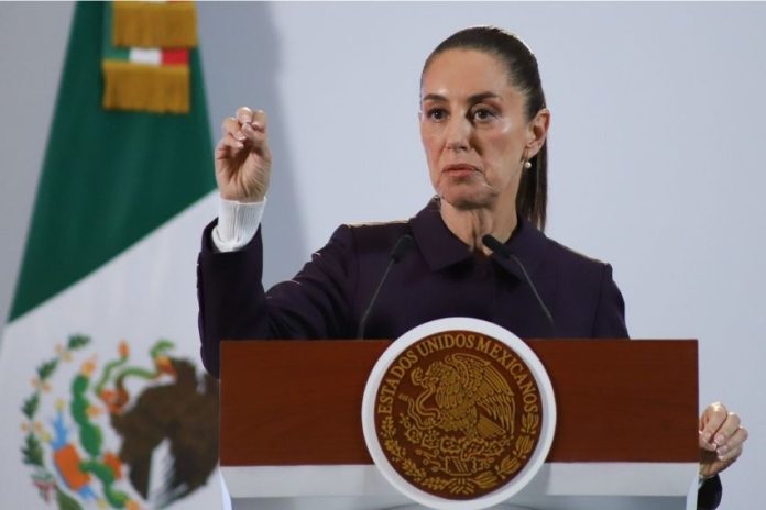 President Claudia Sheinbaum holds up her closed right hand while making a point while standing at the presidential podium during her Nov. 21 press conference at Mexico's National Palace.