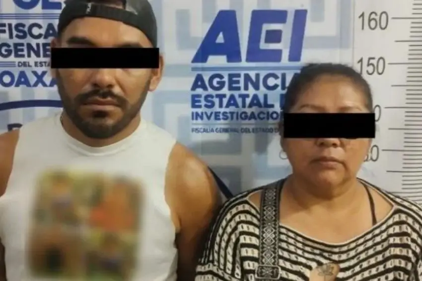 A mugshot of a middle-aged Mexican man and woman standing together in front of a wall with the name of the Oaxaca Attorney General's Office.