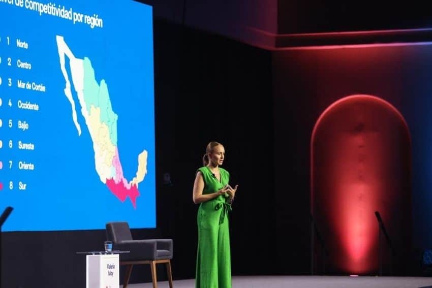 Woman speaking on a stage in a green pantsuit in front of a screen showing the Gulf of California region