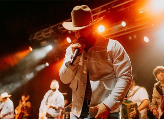 Latin Grammy winner Carín León sings into a microphone while on stage