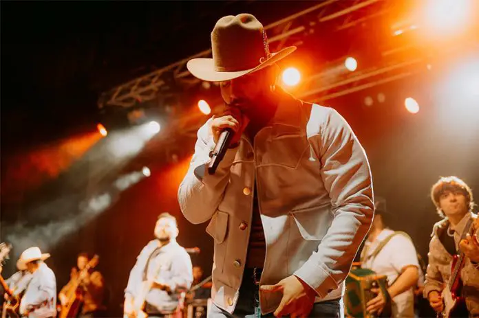 Latin Grammy winner Carín León sings into a microphone while on stage