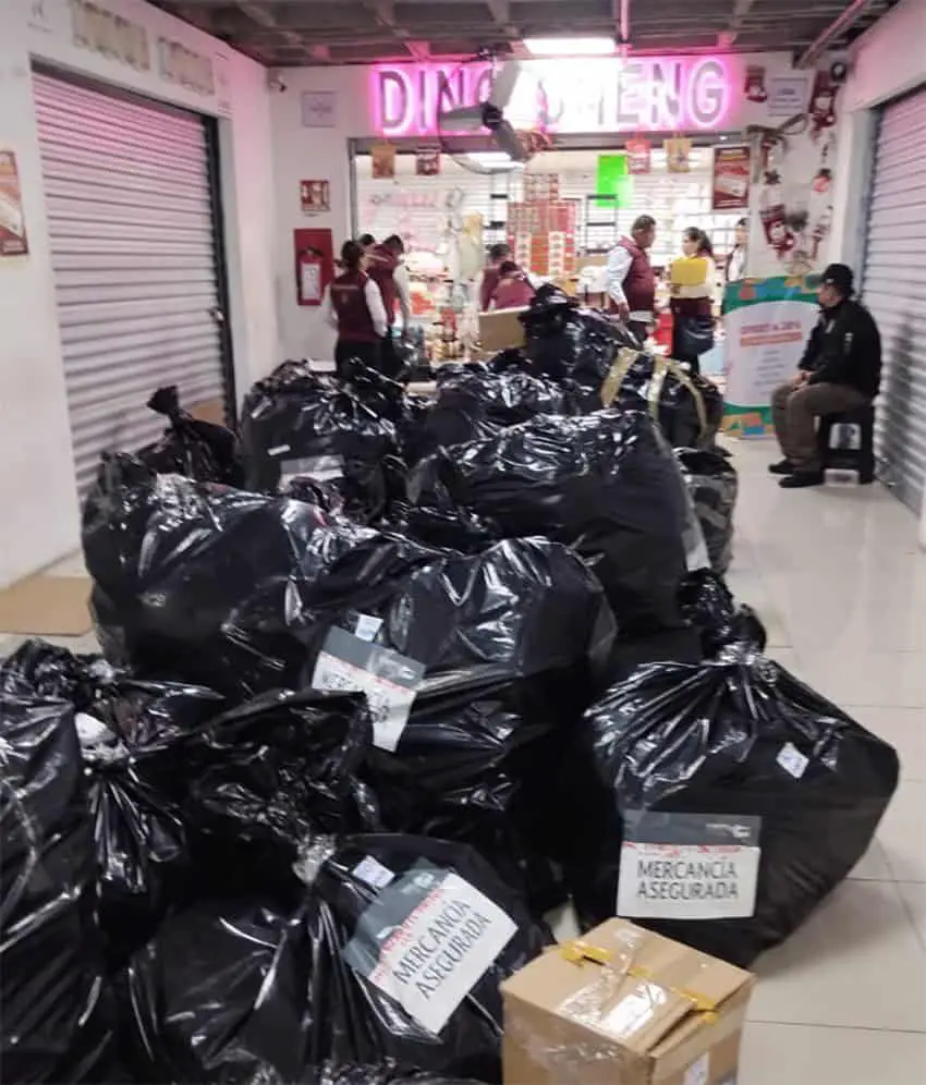 Black plastic bags with labels reading "Mercancía asegurada" in front of a Chinese goods store in a Mexico City mall