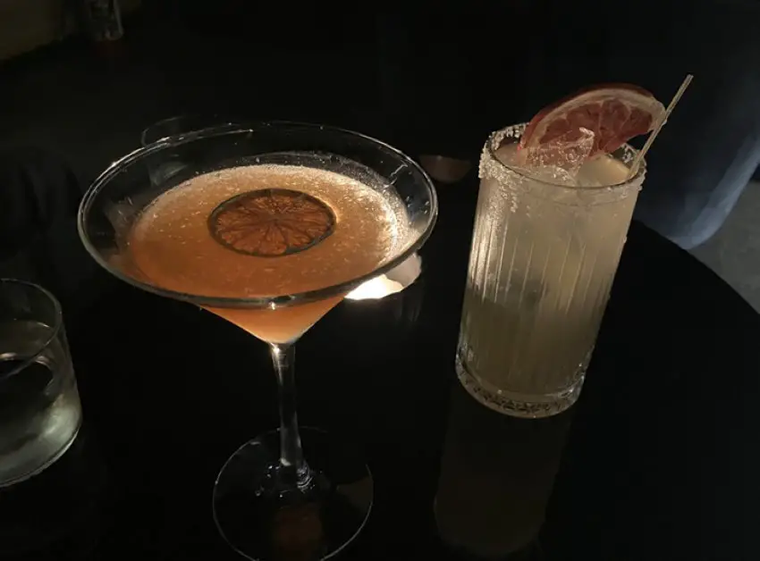 Two cocktails at NOMU speakeasy in Guadalajara, one served in a martini glass and the other in a highball glass