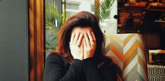 A young woman covers her face in embarrassment