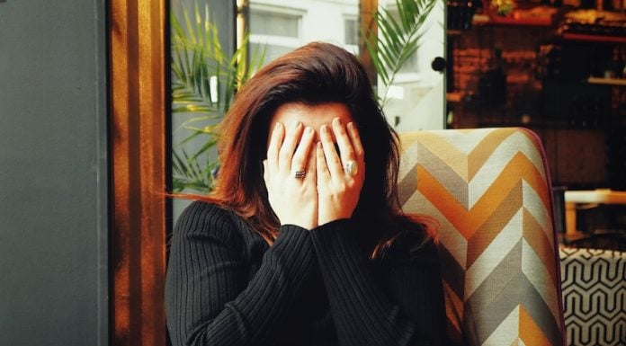 A young woman covers her face in embarrassment