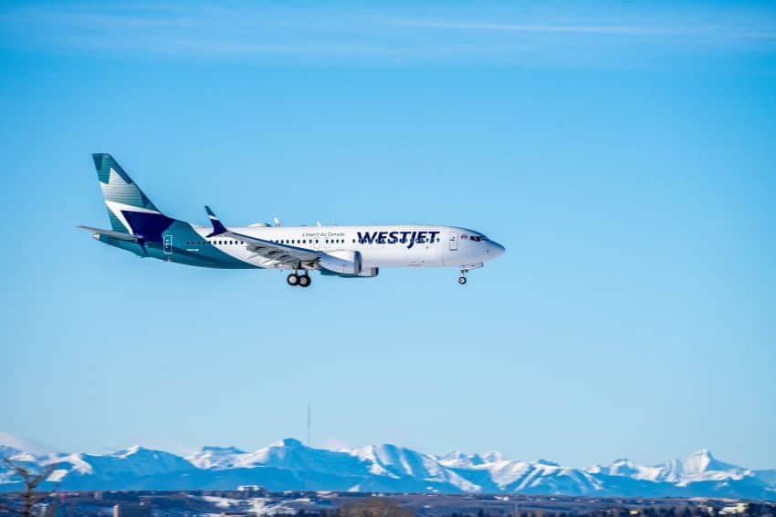 A WestJet plan flies over mountains