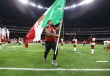 A football player runs with a Mexican flag across the field of Mexico City's Aztec Stadium