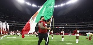 A football player runs with a Mexican flag across the field of Mexico City's Aztec Stadium