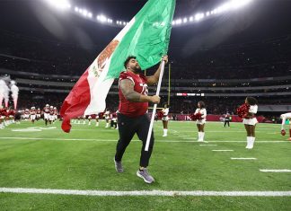 A football player runs with a Mexican flag across the field of Mexico City's Aztec Stadium