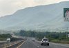 An SUV drives down a highway in Mexico towards distant green mountains