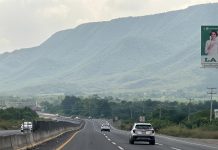 An SUV drives down a highway in Mexico towards distant green mountains