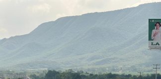 An SUV drives down a highway in Mexico towards distant green mountains