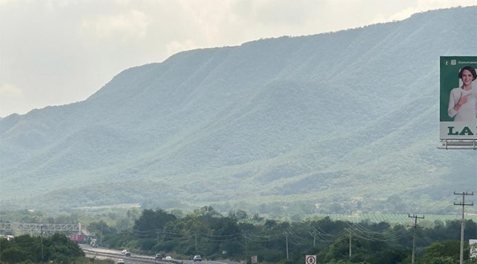 An SUV drives down a highway in Mexico towards distant green mountains