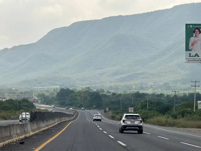 An SUV drives down a highway in Mexico towards distant green mountains