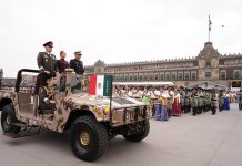 Claudia Sheinbaum rides in a camo military jeep with two military leaders at the Revolution Day parade in Mexico City's main plaza