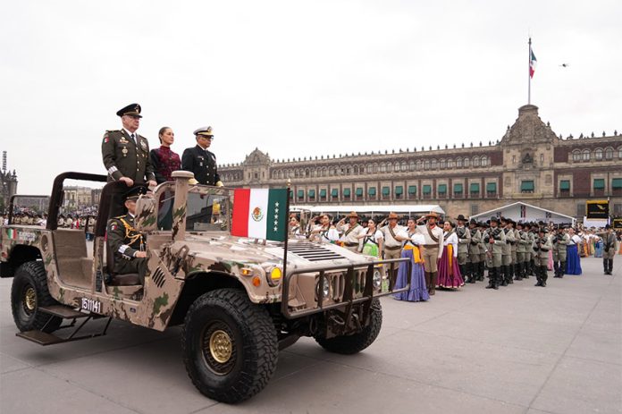 Claudia Sheinbaum rides in a camo military jeep with two military leaders at the Revolution Day parade in Mexico City's main plaza