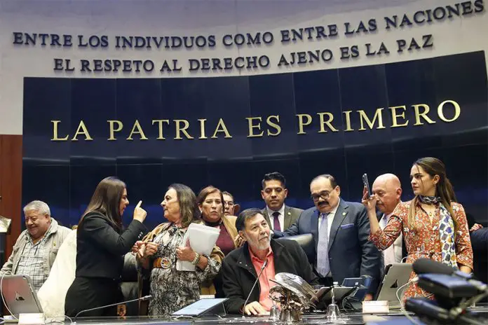 Senate President Gerardo Fernández Noroña, of the Morena party, sits on a legislative dias in front of the words 