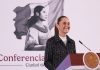 Mexico's President Claudia Sheinbaum stands at a podium smiling during her morning press conference.