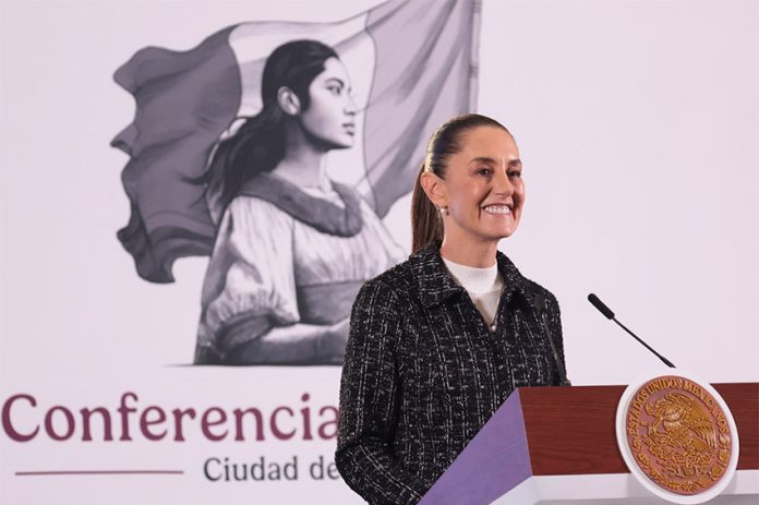 Mexico's President Claudia Sheinbaum stands at a podium smiling during her morning press conference.