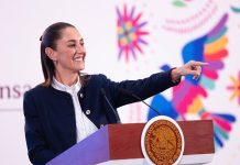 President Claudia Sheinbaum stands at a podium and points to the audience during her Friday morning mañanera, or press conference.