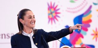 President Claudia Sheinbaum stands at a podium and points to the audience during her Friday morning mañanera, or press conference.