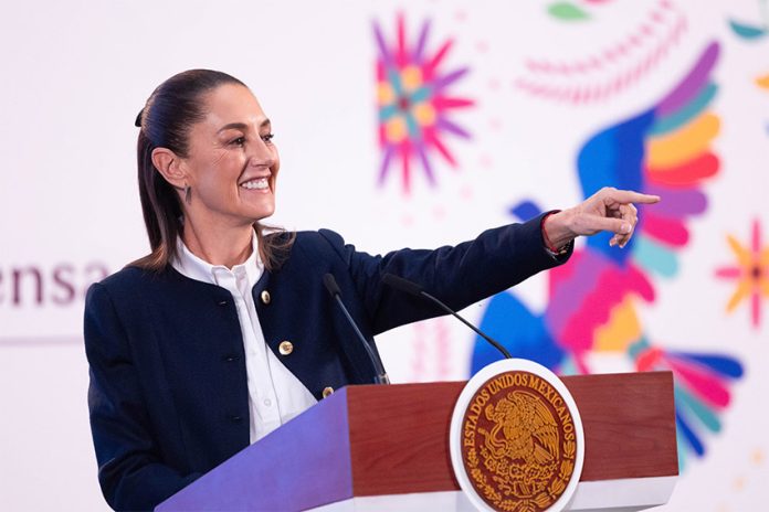 President Claudia Sheinbaum stands at a podium and points to the audience during her Friday morning mañanera, or press conference.