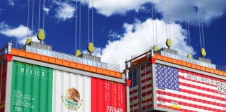 Illustration of two shipping containers hanging by cables in the air. The front of the container on stage left is painted with he flag of Mexico. The container on stage right is painted with the flag of the United States.