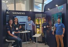 Young Siemens Mexico employees smile and pose for a photo with a tank full of experimentally grown lettuce