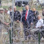 Presidential candidate Donald Trump looks through border fencing in El Paso, Texas, during a campaign stop, surrounded by Texas rangers and border patrol agents