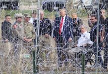 Presidential candidate Donald Trump looks through border fencing in El Paso, Texas, during a campaign stop, surrounded by Texas rangers and border patrol agents