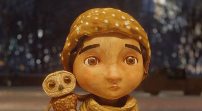 A stop animation still of a little boy in a scarf and and hat with a small owl on his shoulder from the Alfonso Cuaron short film "An Almost Christmas Story"