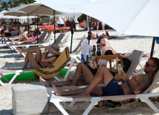 International tourists lay in a row on a sunny Cancún beach