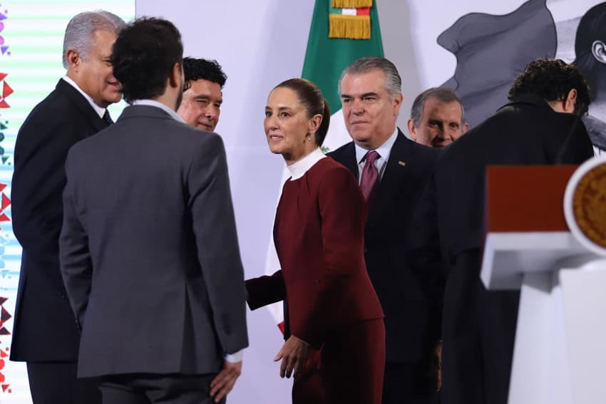 Mexico's President Claudia Sheinbaum standing near her presidential podium, surrounded by five men who are leaders of Mexico's labor sector