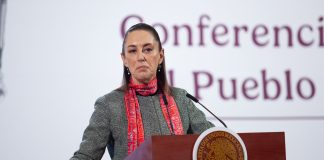 Mexican President Claudia Sheinbaum lead her daily press briefing from a podium, wearing a sweater and scarf