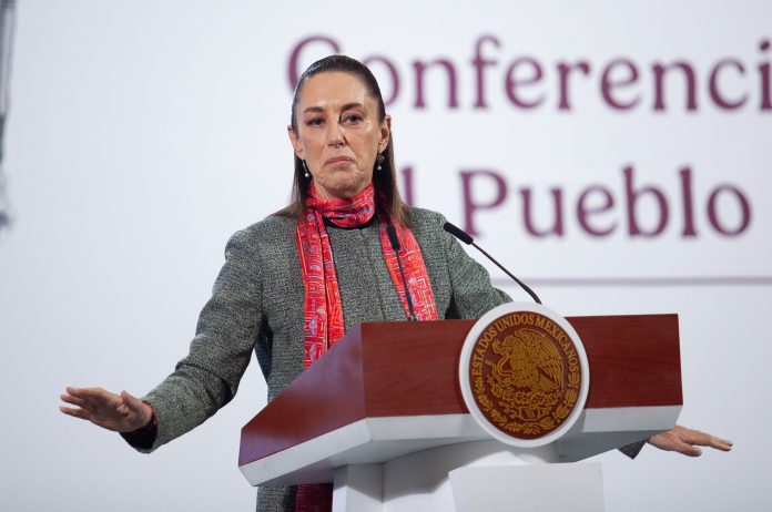 Mexican President Claudia Sheinbaum lead her daily press briefing from a podium, wearing a sweater and scarf