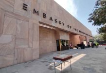 Facade of the new US Embassy in Mexico City. The front of the building is made with pink Mexican cantera stone arranged in rectangles of different sizes and faces a wide courtyard.