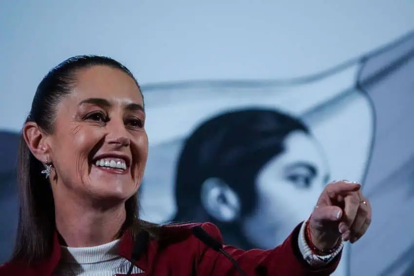 Mexico's President Claudia Sheinbaum at her daily press conference, pointing and smiling.