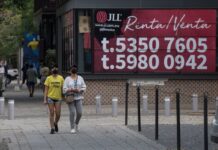 two people walkin gby a for rent sign
