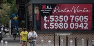 two people walkin gby a for rent sign