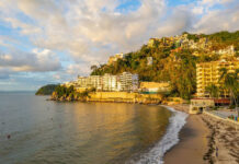 Coastal view of a sandy beach with resorts and hillside homes in Puerto Vallarta, Mexico.