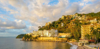 Coastal view of a sandy beach with resorts and hillside homes in Puerto Vallarta, Mexico.